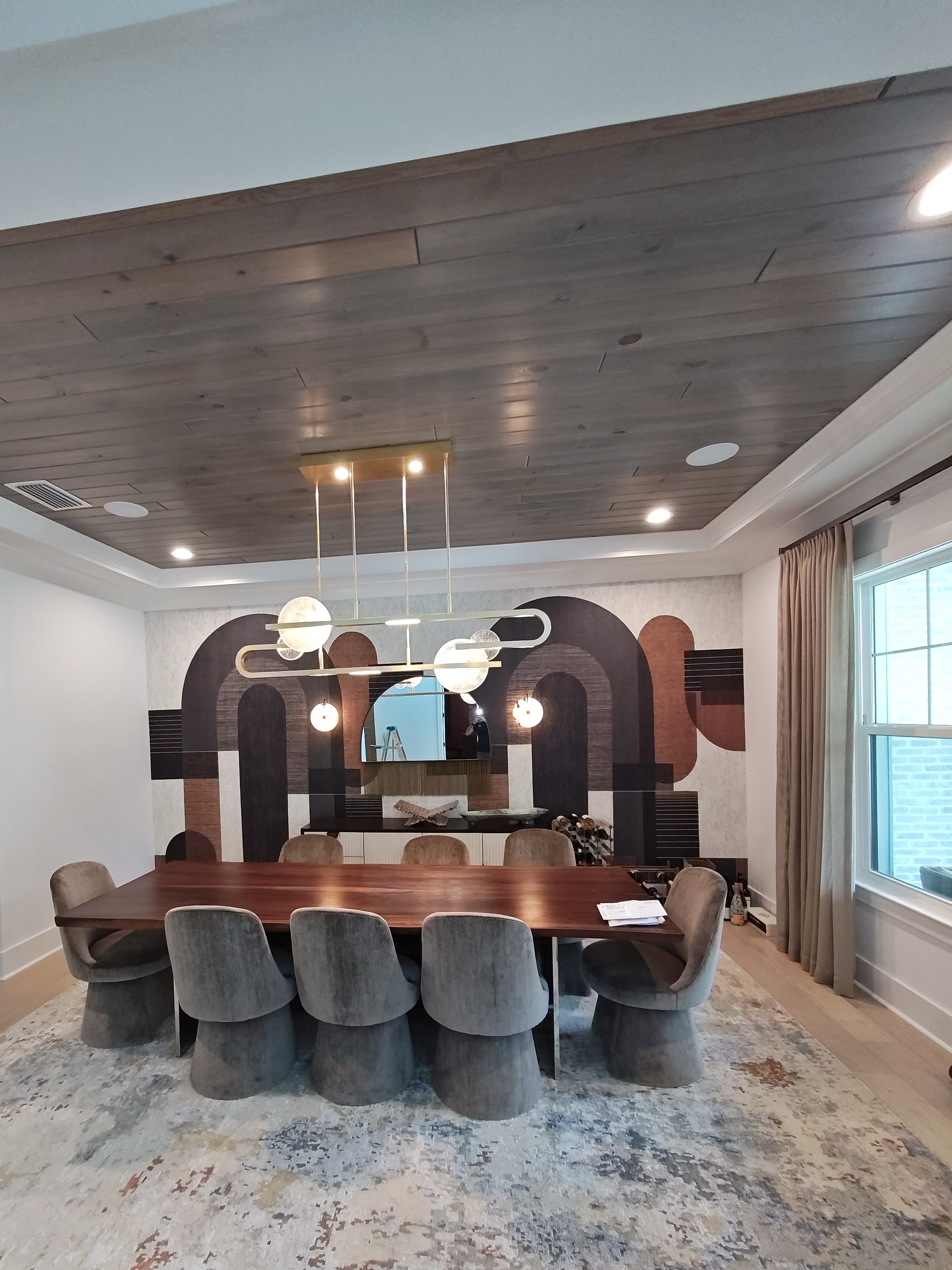 Linear pendant over a dining table beneath a wood tray ceiling