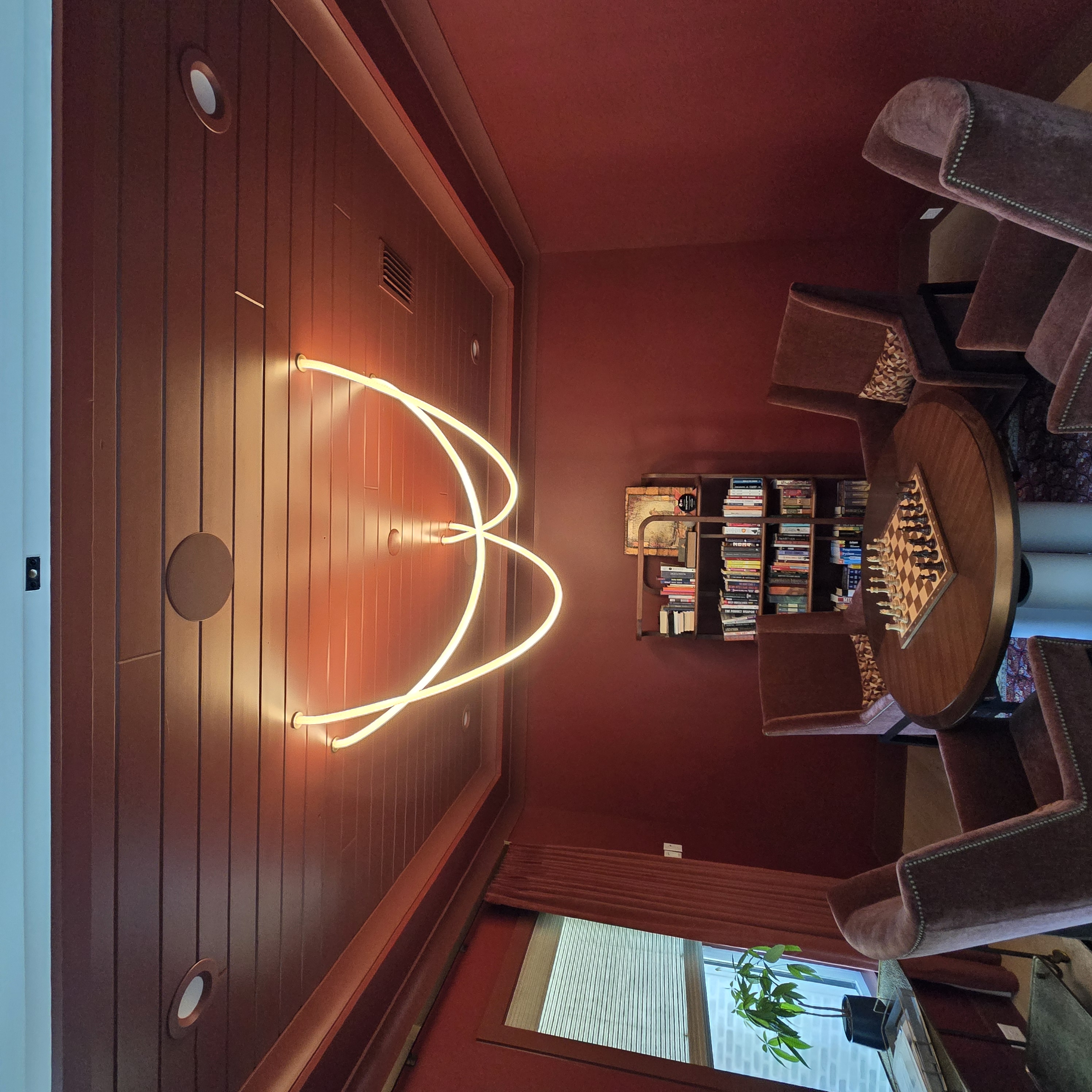 Neon arch light feature in a wood-paneled library and game room