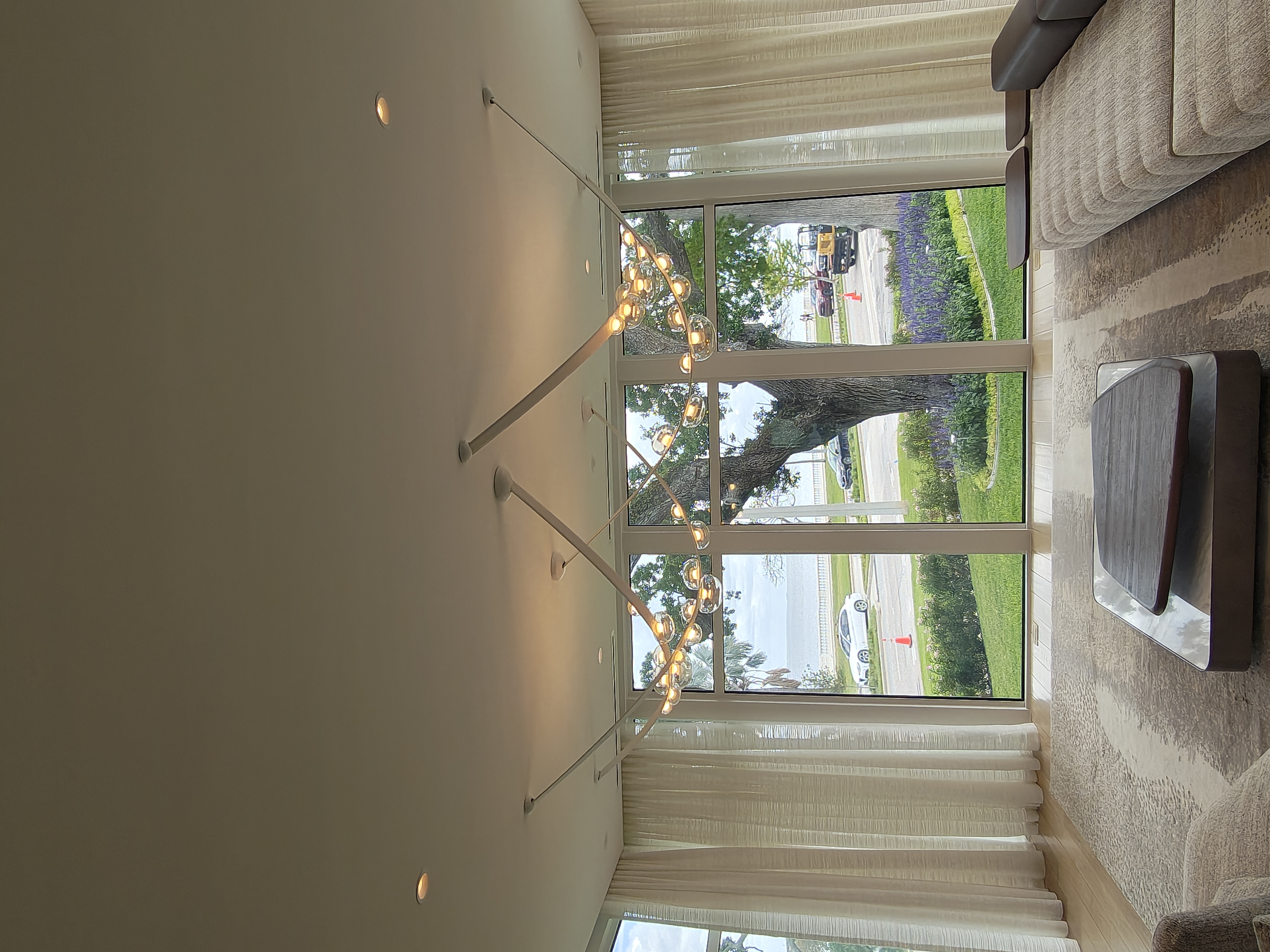 Cascading cluster chandelier in a two-story stairwell beside tall windows