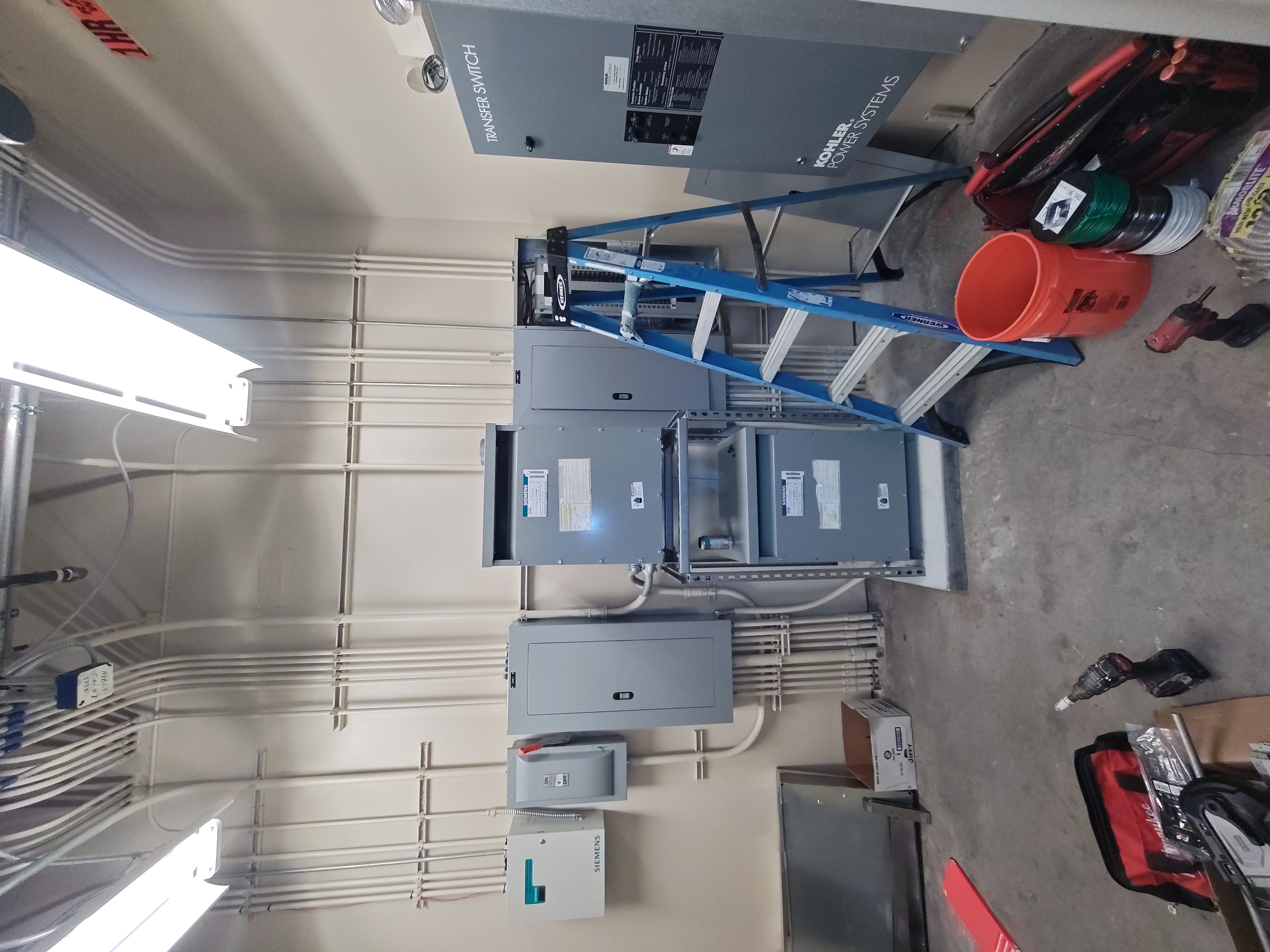 Distribution panels and a Kohler transfer switch wired with conduit in a commercial power room
